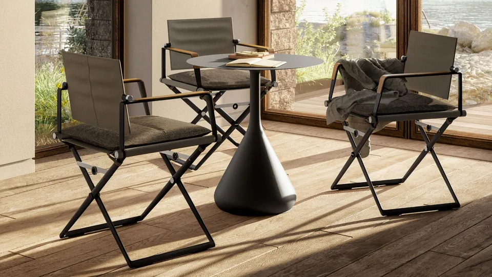 Dedon Satellite outdoor table with an HPL top and ceramic base beside woven chairs